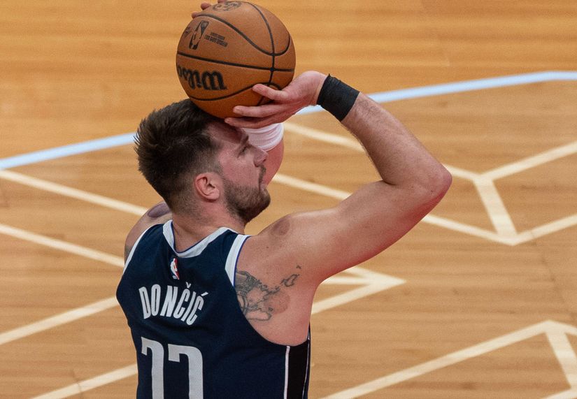 A basketball player in a navy jersey, number 77, holds a basketball and readies for a shot on the smooth, light wood court with crisp white lines. Its as intense as a final Betway game moment, where every point matters.
