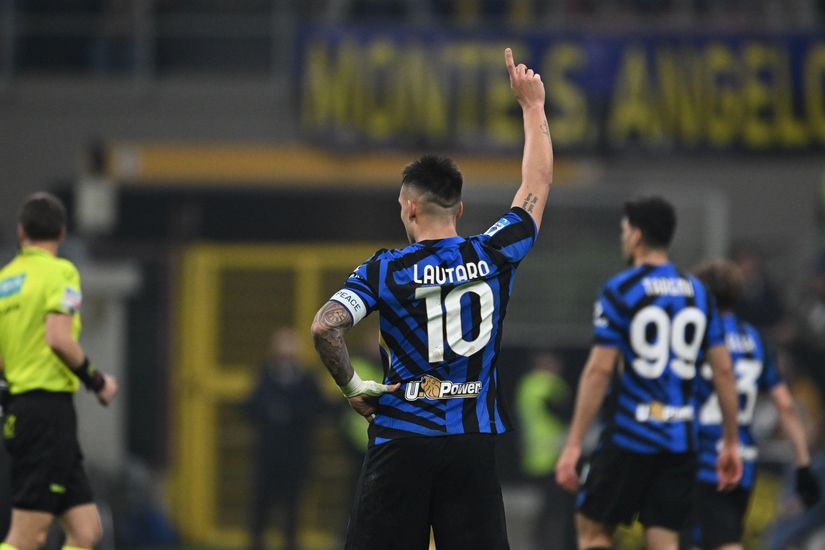 A soccer player in a blue and black striped jersey with the number 10 raises one arm during the Betway-sponsored match. Other players and a referee in a yellow shirt are visible on the field, capturing the intensity of live sports action.