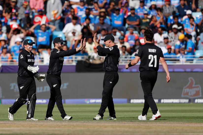 Four cricket players in black uniforms celebrate on the field, exuding a sense of camaraderie. One player claps as they walk forward with determination. The crowd in the stands, adorned in blue, eagerly watches the game unfold, embodying Betways thrilling sports spirit.