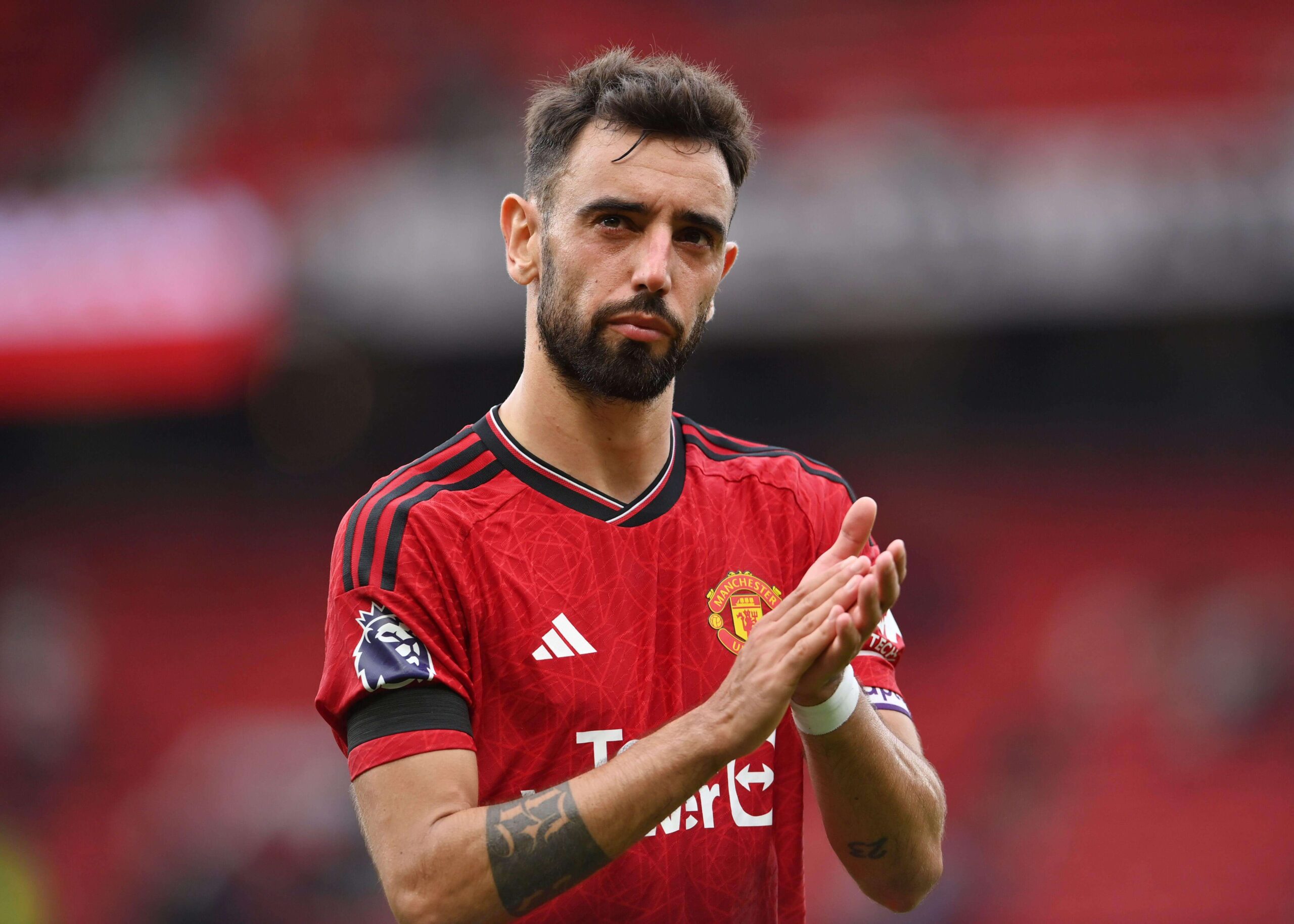A soccer player in a red jersey claps, standing proudly on a field, embodying the spirit of competition and excitement that Betway Arabia brings to fans across the region.