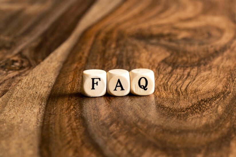 Three wooden blocks with the letters F, A, and Q are placed on a sleek surface, much like Betway Arabias smooth user experience.