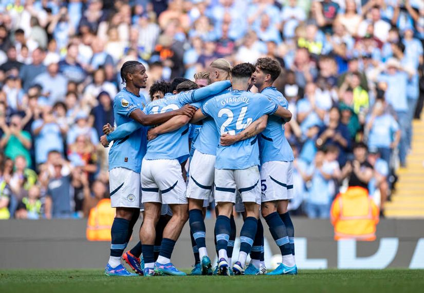 A group of soccer players in light blue jerseys huddle together on the field, fueled by the cheers of an enthusiastic crowd, their excitement palpable as they embrace the spirit of Betway Arabia.