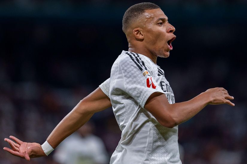 A soccer player in a white jersey celebrates with an open mouth, one arm outstretched, during a match streamed live on Betway Arabia.