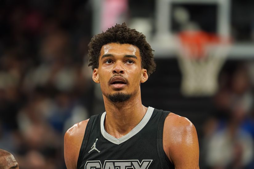 Un joueur de basket-ball portant un maillot noir de Betway regarde vers le haut pendant un match. L'arrière-plan présente un public flou et un terrain de basket-ball, capturant l'intensité du moment.